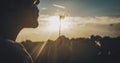 Close up of people blowing big dandelion flower with sunset light and field in background. Outdoor leisure activity and nature Royalty Free Stock Photo