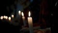 Close up of people sitting in a row and holding burning candles. Stock footage. Religious background with men and women