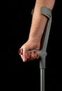 Close up of person hand with forearm crutches. Black isolated background vertical image. Side view