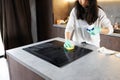 Close-up Of Person Hands Cleaning Induction Stove In Kitchen With Spray Bottle And Sponge. Royalty Free Stock Photo