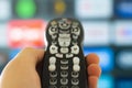 Close up of a person holding a control remote with a television screen on the background Royalty Free Stock Photo