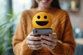 Close up of a person holding a mobile phone with a cute emoji face. Online social media