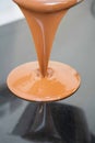 Close-up of a person pouring melted liquid chocolate onto a bowl