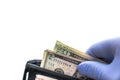 Close up of person pulling cash including a five and two twenty dollar bills out of a black leather wallet wearing a blue latex Royalty Free Stock Photo