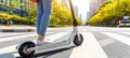 Close up of person riding eco friendly e scooter in urban city street on bright summer day