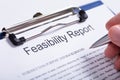 Person`s Finger Holding Pen Over Feasibility Report Royalty Free Stock Photo