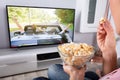 Person`s Hand Holding Popcorn While Movie Plays On Television Royalty Free Stock Photo