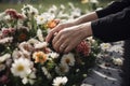 close-up of a person& x27;s hand, placing fresh flowers on the grave