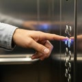 A close up of a person s hand pressing a lighted button inside an elevator Royalty Free Stock Photo