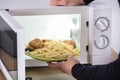 Person Putting Fried Food Inside Microwave Oven