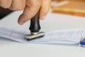 Close-up Of Person`s Hand Stamping On Approved Application Form or Notary public in office documents for signing approval. Royalty Free Stock Photo