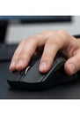 Close-up of a person\'s hand using a black computer mouse on a dark surface. The Royalty Free Stock Photo