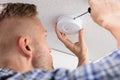 Person`s Hand Using Screwdriver To Install Smoke Detector Royalty Free Stock Photo