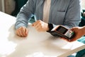 Close-up of a person& x27;s hands completing a contactless payment using a smartwatch at a point of sale terminal