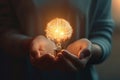 A close-up of a person\'s hands holding a glowing brain shaped light bulb, representing innovative ideas