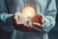 A close-up of a person\'s hands holding a glowing brain shaped light bulb, representing innovative ideas