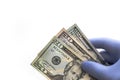 Close up of person wearing a blue latex glove holding a hundred, fifty and twenty dollar bill fanned out and handing over for Royalty Free Stock Photo