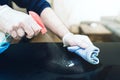 Close-up of person wearing disposable one-way gloves using disinfectant spray to clean table surface