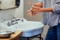 Close-up of a person& x27;s hands being washed with soap and water at a sink.