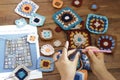 Close-up of a person's hands creating a colorful crocheted square using yarn.