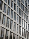 Close up perspective detail of tall high rise modern apartment building with geometric metallic cladding and dark windows