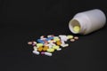 Close up of pharmaceutical medical pills next to a drug bottle in a dark background