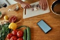 Close up of phone with blank screen on the table. Man cutting onion on chopping board, using smartphone app while Royalty Free Stock Photo