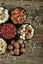 Close up phot of nut mix cashews, pistachios, almonds, macadamia, walnuts and sunflower seeds in bowls on wooden table