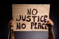 Close up photo of afro american person hand hold cardboard banner with text no justice no peace continue fighting