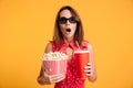 Close-up photo of amazed beautiful young woman in 3d glasses holding cola and popcorn and looking camera Royalty Free Stock Photo