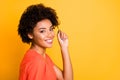 Close up photo of amazing dark skin lady with beaming smile playing with curl wear orange v neck t-shirt isolated yellow