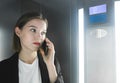 Close-up photo of ambitious office worker talking on her smartphone in the elevator. Portrait of a young female employee talking Royalty Free Stock Photo