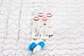 Close-up photo of ampoules with medicine and pills on EKG graph