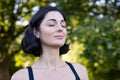 Close-up photo of a beautiful and athletic woman standing relaxed outside in the park and resting from training and Royalty Free Stock Photo