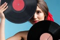 Close up photo of a beautiful girl likes music holding two vynil music records hiding partly her face over blue Royalty Free Stock Photo