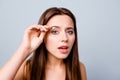 Close up photo of beautiful pretty cute charming woman using tweezers for plucking her eyebrows, isolated on grey background Royalty Free Stock Photo