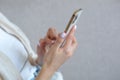 A close-up photo of a beautiful woman's hand with a white manicure is using phone Royalty Free Stock Photo