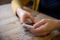 Close up photo of beautiful young woman sitting cozy at wooden table. Girl using touch screen smartphone.