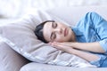 A young woman sleeps and rests with closed eyes on a sofa on a pillow, hands folded under her head Royalty Free Stock Photo