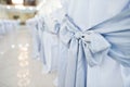 Close-up photo of big blue bows tied on white wedding chairs. Royalty Free Stock Photo