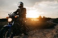 Close-up photo of biker sitting on motorcycle in sunset on the country road. Copy space. Royalty Free Stock Photo