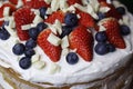 naked cake with a white cream strawberries blueberries and a white chocolate