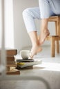 Close up photo of books and cup of coffee lying on floor. Girl`s legs on chair background. Royalty Free Stock Photo