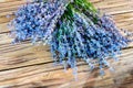 Close-up photo of a bouquet of lavender, lying on another bouquet of lavender on a wooden background