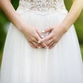 Close-up photo of bride`s hands with golden engagement ring on beautiful white wedding dress Royalty Free Stock Photo