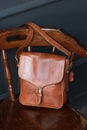 close-up photo of brown messanger leather bag on a wooden chair