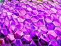 A close-up photo of a buildings facade featuring an intricate pattern of hexagonal tiles in a vibrant purple hue