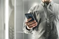 Close up photo of a busy man using smartphone in the elevator. Ambitious office worker texting by her phone in the lift. Focus on