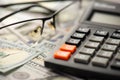 Close up photo of calculator and eyeglasses on dollar bills