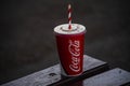 Close up photo of Cola paper cup with straw on a wooden bench in Bucharest, Romania, 2019